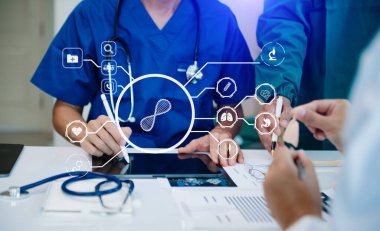 Tıp teknolojisi ekip toplantısı konsepti. Doktor El, akıllı telefon, modern dijital tablet ve grafik çizelgesi arayüzü ve sanal simge diyagramı olan dizüstü bilgisayarla çalışıyor.