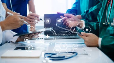 Tıp teknolojisi ekip toplantısı konsepti. Doktor El, akıllı telefon, modern dijital tablet ve grafik çizelgesi arayüzü ve sanal simge diyagramı olan dizüstü bilgisayarla çalışıyor.
