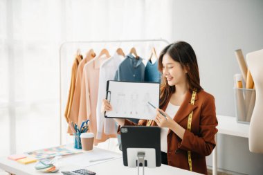 Boyunlarında santimetre boyayla çalışan ve tablet ve akıllı telefon tutan çeşitli kadın moda tasarımcıları. bağımsız yaratıcı tasarım işi. 