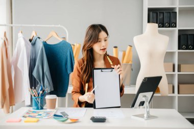 Boyunlarında santimetre boyayla çalışan ve tablet ve akıllı telefon tutan çeşitli kadın moda tasarımcıları. bağımsız yaratıcı tasarım işi. 