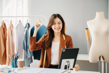 Boyunlarında santimetre boyayla çalışan ve tablet ve akıllı telefon tutan çeşitli kadın moda tasarımcıları. bağımsız yaratıcı tasarım işi. 