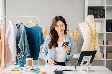 Boyunlarında santimetre boyayla çalışan ve tablet ve akıllı telefon tutan çeşitli kadın moda tasarımcıları. bağımsız yaratıcı tasarım işi. 