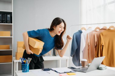 Başlangıçta küçük işletme KOBİ 'si, akıllı telefon ya da tablet kullanan girişimci kadın ürün kutusunu paketlemek için online alışveriş siparişini alıp kontrol ediyor.