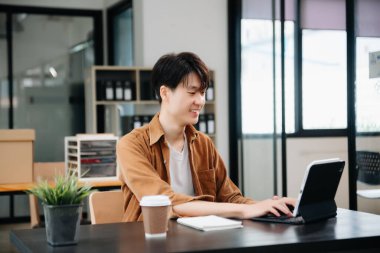 Ofisteki masasında oturan Asyalı genç bir adamın portresi..