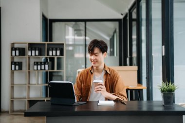 Ofisteki masasında oturan Asyalı genç bir adamın portresi..