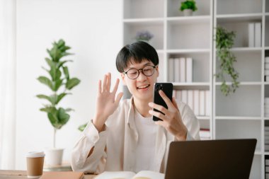 Modern ofiste masasında oturan Asyalı genç bir adamın portresi..