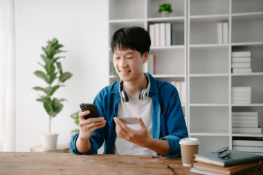 Man using smart phone for mobile payments online shopping,omni channel,sitting on table,virtual icons graphics interface screen
