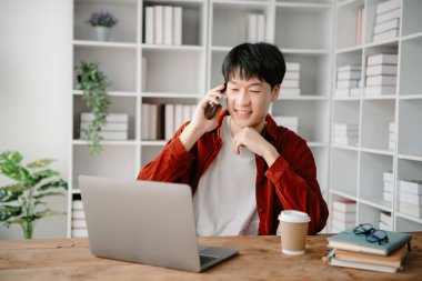 Modern ofiste masasında oturan Asyalı genç bir adamın portresi..