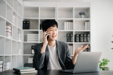 Ofisteki masasında oturan Asyalı genç adamın portresi.