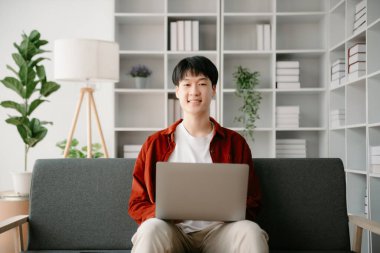 Modern ofiste masasında oturan Asyalı genç bir adamın portresi..