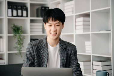 Modern ofiste laptopla, tabletle çalışan ve kağıda not alan genç bir iş adamı..