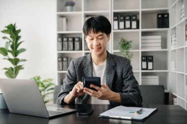 Ofisteki masasında oturan Asyalı genç adamın portresi.