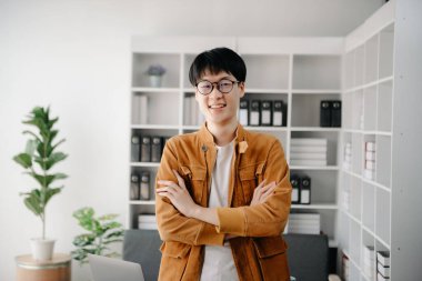 Ofisteki masasında oturan Asyalı genç adamın portresi.