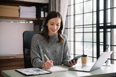 Kendine güvenen iş uzmanı çekici, gülümseyen genç bir kadın yaratıcı ofiste elinde dijital tablet tutuyor.