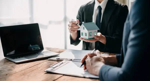 Real estate broker agent presenting and consult to customer to decision making sign insurance form agreement, home model, concerning mortgage loan offer