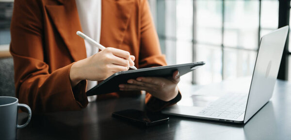 Предпринимательница вручную работает с новым современным компьютером, используя смартфон и планшет как концепцию в оффике