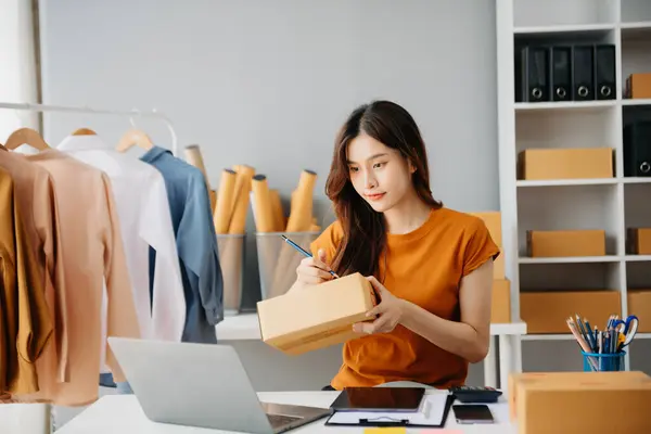 Çevrimiçi mağaza işleten genç kadın akıllı telefon ya da tablet kullanarak küçük işletme KOBİ 'si başlat, çevrimiçi satın alma oranları al ve kontrol et