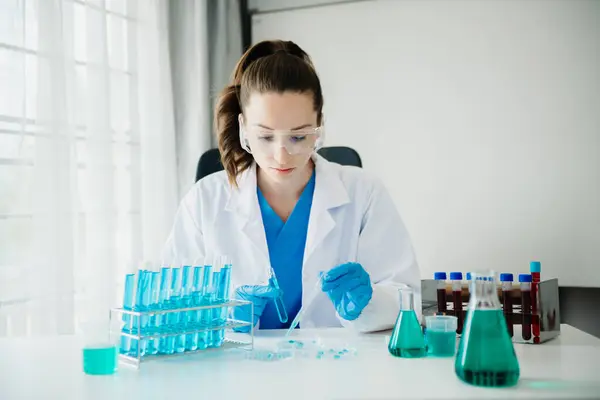 Modern tıbbi araştırma laboratuvarı. Kadın bilim adamı mikro pipetlerle çalışıyor biyokimyasal örnekleri analiz ediyor, ileri bilim kimya laboratuvarı