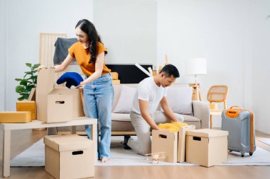 Büyük kutuları olan genç bir çift yeni bir eve taşınıyor, çift için yeni bir daire, genç Asyalı erkek ve kadın yeni ev için kanepenin taşınmasına yardım ediyorlar.