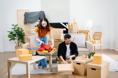 Büyük kutuları olan genç bir çift yeni bir eve taşınıyor, çift için yeni bir daire, genç Asyalı erkek ve kadın yeni ev için kanepenin taşınmasına yardım ediyorlar.