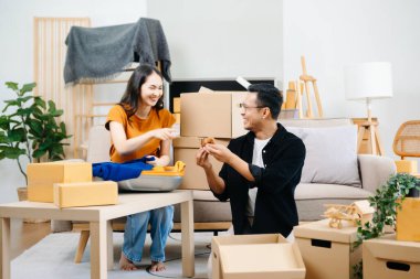 Büyük kutuları olan genç bir çift yeni bir eve taşınıyor, çift için yeni bir daire, genç Asyalı erkek ve kadın yeni ev için kanepenin taşınmasına yardım ediyorlar.