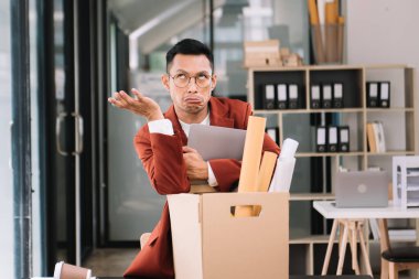 Mutlu ve heyecanlı genç Asyalı erkek ofis çalışanı istifasını kutluyor, kişisel eşyalarını taşıyor. Modern ofiste işi bırakmak, değiştirmek ya da şirket kurmak.