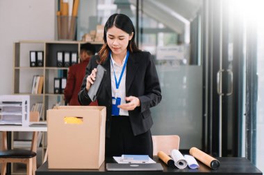 Mutlu ve heyecanlı genç Asyalı kadın ofis çalışanı istifasını kutluyor, kişisel eşyalarını taşıyor. Modern ofiste işi bırakmak, değiştirmek ya da şirket kurmak.
