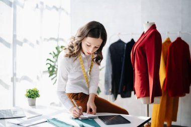 Boyunlarında santimetre boyayla çalışan ve tablet ve akıllı telefon tutan çeşitli kadın moda tasarımcıları. bağımsız yaratıcı tasarım işi.