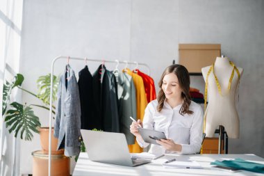 Boyunlarında santimetre boyayla çalışan ve tablet ve akıllı telefon tutan çeşitli kadın moda tasarımcıları. bağımsız yaratıcı tasarım işi.