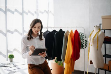 Boyunlarında santimetre boyayla çalışan ve tablet ve akıllı telefon tutan çeşitli kadın moda tasarımcıları. bağımsız yaratıcı tasarım işi.