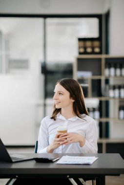 Güzel bir kadın çalışma yerinde otururken dizüstü bilgisayar ve tablet kullanıyor. İşine odaklan..