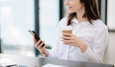 Güzel bir kadın çalışma yerinde otururken dizüstü bilgisayar ve tablet kullanıyor. İşine odaklan..