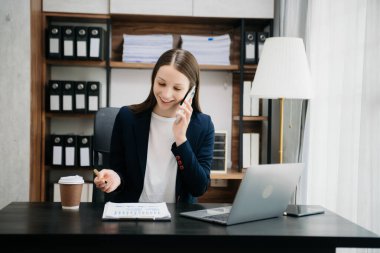  Güzel beyaz kadın çalıştığı yerde otururken dizüstü bilgisayar ve tablet kullanıyor. İşine odaklan.