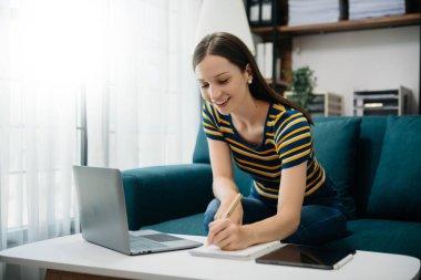 Ofiste çalışan Kafkas iş kadını. Not defteri, tablet ve dizüstü bilgisayarla. İç işlerindeki kanepede.