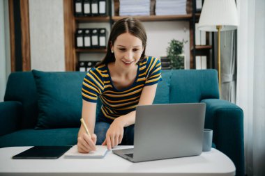 Ofiste çalışan Kafkas iş kadını. Not defteri, tablet ve dizüstü bilgisayarla. İç işlerindeki kanepede.