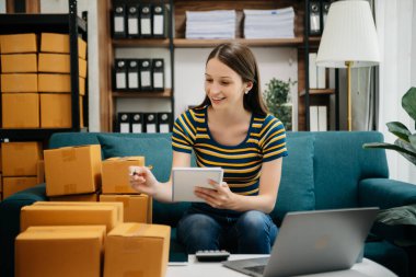 Beyaz kadın KOBİ akıllı telefon ya da tablet kullanarak çalışıyor online alışveriş siparişlerini alıyor ve kontrol ediyor, serbest iş çevrim içi konsepte