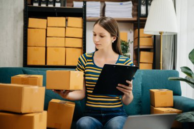 Beyaz kadın KOBİ akıllı telefon ya da tablet kullanarak çalışıyor online alışveriş siparişlerini alıyor ve kontrol ediyor, serbest iş çevrim içi konsepte