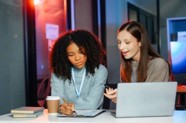 İş kadını takım toplantısını yönetiyor ve birlikte çalışma ofisinde mali durumu iyi olan tablet ve dizüstü bilgisayar kullanıyor. overtim