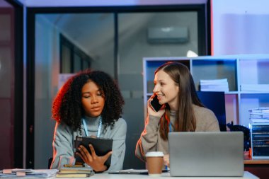 İş kadını takım toplantısını yönetiyor ve birlikte çalışma ofisinde mali durumu iyi olan tablet ve dizüstü bilgisayar kullanıyor. overtim