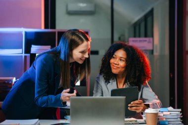 Akıllı telefondan konuşan ve ofiste dizüstü bilgisayar kullanan iki iş adamı. overtim