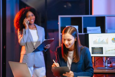 Akıllı telefondan konuşan ve ofiste dizüstü bilgisayar kullanan iki iş adamı. overtim