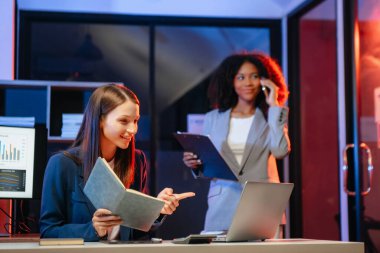 Akıllı telefondan konuşan ve ofiste dizüstü bilgisayar kullanan iki iş adamı. overtim