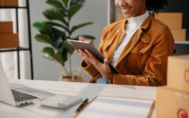  Dizüstü bilgisayar, akıllı telefon ve tablet kullanan ve iş yerindeki internet alışverişinde defter yazan bir kadın eli. Ofiste.