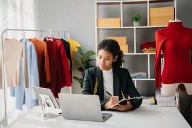 Boyunlarında santimetre boyayla çalışan ve tablet ve akıllı telefon tutan çeşitli kadın moda tasarımcıları. Bağımsız yaratıcı tasarım işi. Ofislerde
