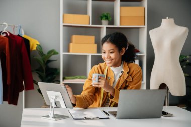 Boyunlarında santimetre boyayla çalışan ve tablet ve akıllı telefon tutan çeşitli kadın moda tasarımcıları. Bağımsız yaratıcı tasarım işi. Ofislerde