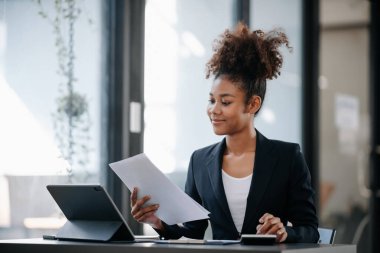  Güzel Afrikalı kadın çalıştığı yerde bilgisayarını ve tabletini kullanıyor. İşine odaklan..