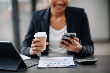 woman using laptop and typing on laptop and holding coffee cup in cafe, home office