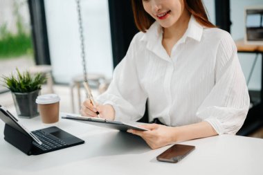 Ofiste bilgisayar, tablet ve akıllı telefon kullanan bir iş kadını. Dijital pazarlama medya mobil uygulaması ve yeni bir başlangıç projesi hakkında tartışmalar. Finans görevi