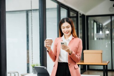 Tablet ve dizüstü bilgisayarda yazan genç ve güzel bir kadın beyaz çalışma masasında oturuyor.