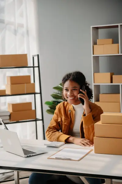 Çevrimiçi mağaza işleten genç Afrikalı kadın akıllı telefon ya da tablet kullanarak küçük işletme KOBİ 'si başlatarak, evdeki çevrimiçi alışveriş siparişlerini alıp kontrol ediyor